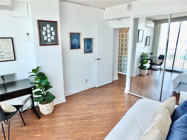 office area with a wall unit AC, light hardwood / wood-style floors, and floor to ceiling windows