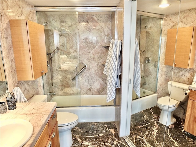 full bathroom with tile walls, vanity, combined bath / shower with glass door, and toilet