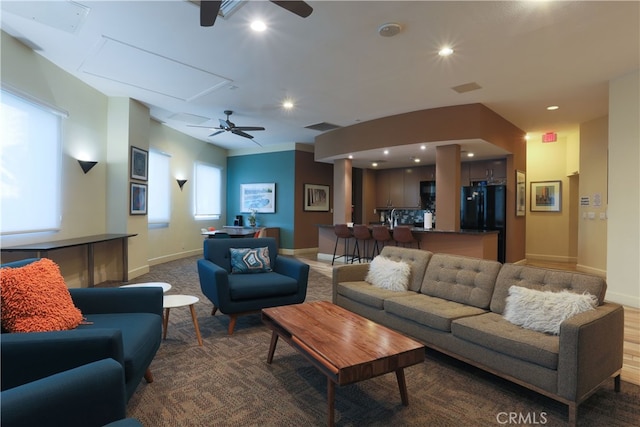 living room featuring ceiling fan and dark colored carpet