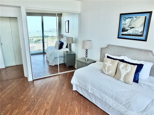 bedroom featuring a closet, hardwood / wood-style flooring, access to outside, and a wall of windows