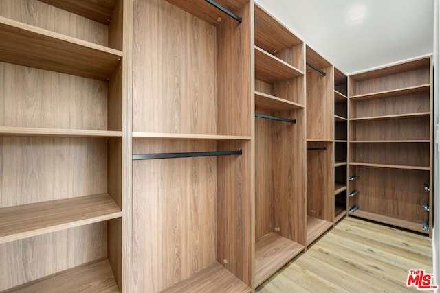 walk in closet with light hardwood / wood-style flooring