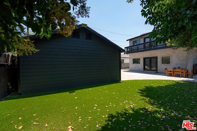 view of yard featuring a balcony, a patio, and french doors