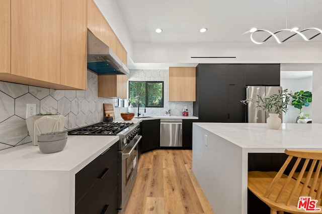 kitchen with a center island, stainless steel appliances, range hood, pendant lighting, and light hardwood / wood-style floors