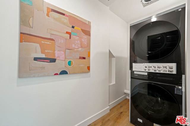 clothes washing area featuring light wood-type flooring and stacked washer and dryer