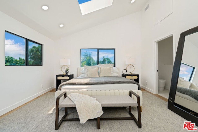 bedroom with light wood-type flooring, connected bathroom, a skylight, and high vaulted ceiling