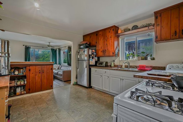 kitchen featuring stainless steel refrigerator, sink, white gas range, and ceiling fan