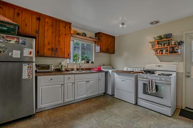 kitchen with washer / clothes dryer, sink, white gas range oven, white cabinetry, and stainless steel refrigerator