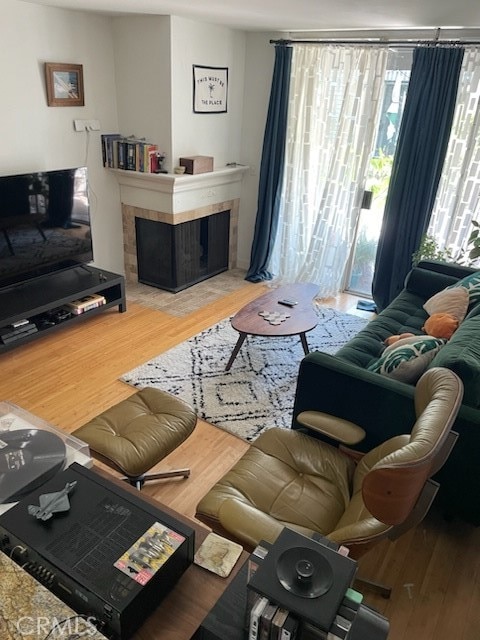 living room with a tiled fireplace and hardwood / wood-style flooring