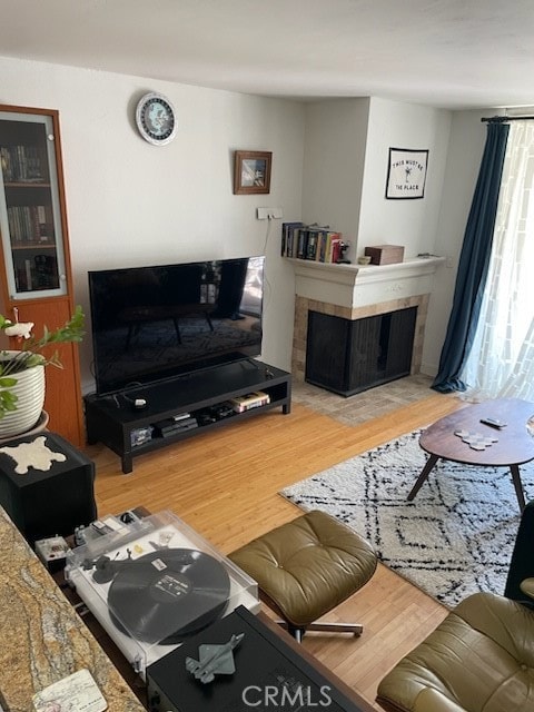 living room with a tiled fireplace and hardwood / wood-style flooring