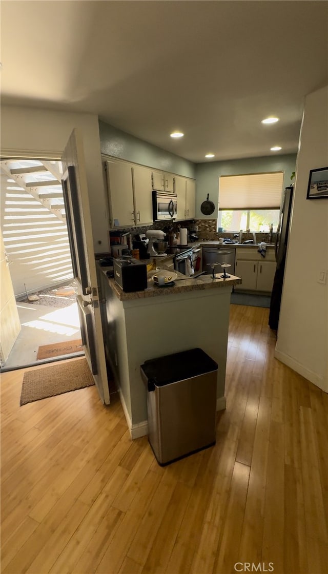 kitchen featuring stainless steel appliances, kitchen peninsula, and hardwood / wood-style floors