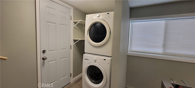 laundry room featuring stacked washer and clothes dryer and hardwood / wood-style flooring