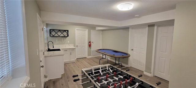 recreation room with sink and light wood-type flooring