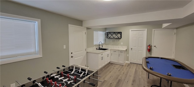 kitchen with light hardwood / wood-style floors, white cabinets, and sink