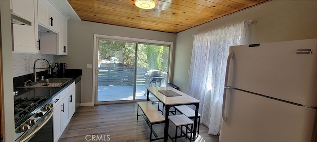 kitchen featuring light hardwood / wood-style floors, stainless steel range, white cabinetry, and white refrigerator