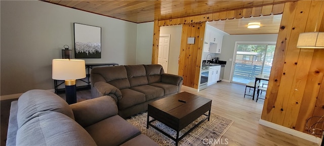 living room featuring light hardwood / wood-style floors, sink, and wooden ceiling