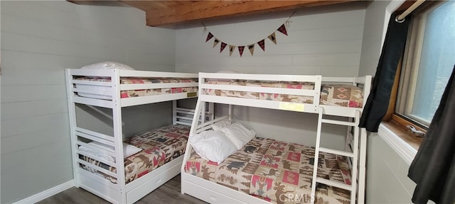 bedroom featuring dark wood-type flooring and beam ceiling