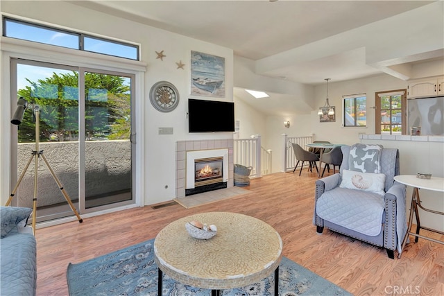 living room with a tiled fireplace and light wood-type flooring