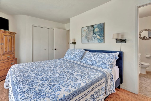 bedroom with light hardwood / wood-style floors, a closet, and ensuite bathroom