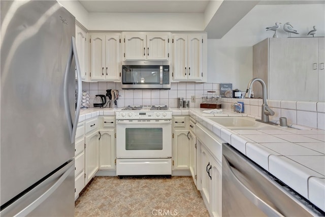 kitchen with tasteful backsplash, appliances with stainless steel finishes, sink, and tile counters