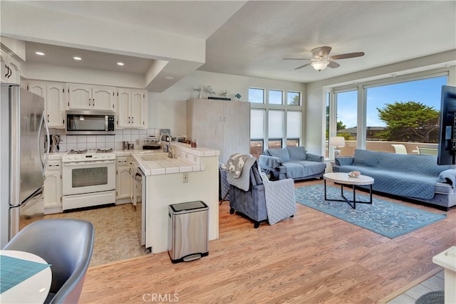 kitchen featuring light hardwood / wood-style floors, appliances with stainless steel finishes, tile countertops, and backsplash