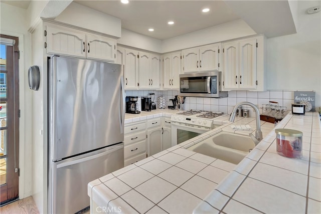 kitchen with tile countertops, appliances with stainless steel finishes, and backsplash