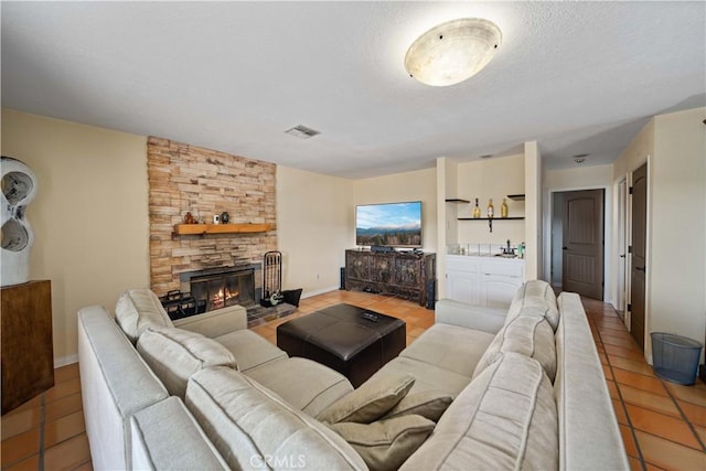 tiled living room with a stone fireplace and a textured ceiling