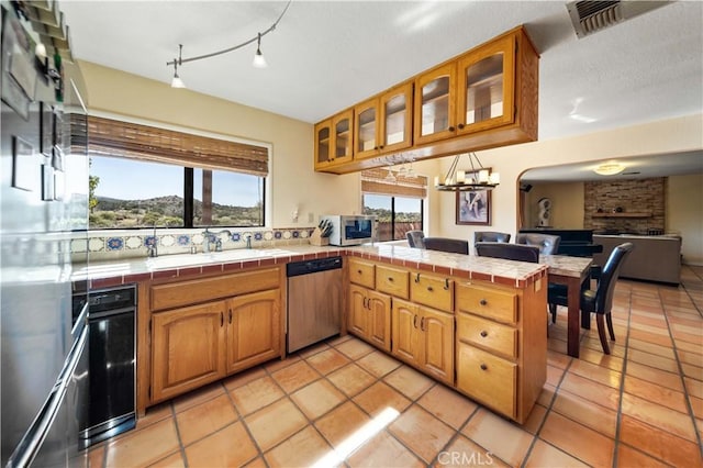 kitchen featuring kitchen peninsula, appliances with stainless steel finishes, tile countertops, and a wealth of natural light