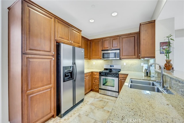 kitchen featuring light stone countertops, sink, stainless steel appliances, backsplash, and kitchen peninsula