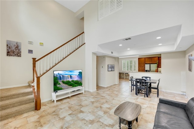 living room with a towering ceiling and a raised ceiling