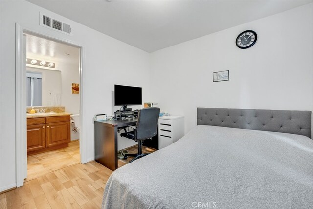 bedroom featuring ensuite bath, light hardwood / wood-style flooring, and sink