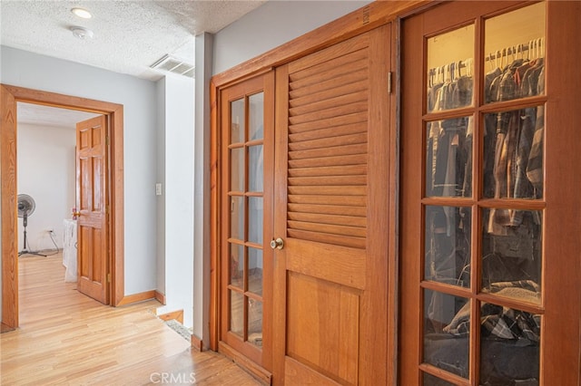 hall with light hardwood / wood-style flooring and a textured ceiling