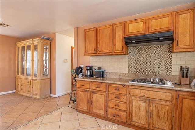 kitchen with stainless steel gas stovetop, light tile patterned flooring, and backsplash