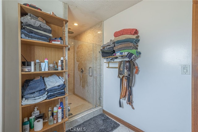 bathroom featuring a shower with door, a textured ceiling, and tile patterned flooring