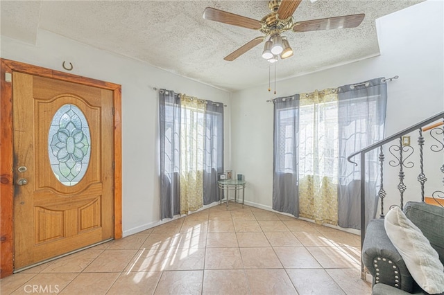 entrance foyer with light tile patterned flooring, a textured ceiling, and ceiling fan