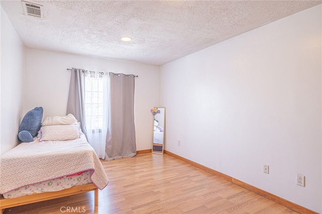 bedroom with light hardwood / wood-style flooring and a textured ceiling