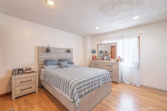 bedroom with a textured ceiling and light wood-type flooring