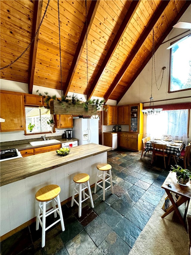 kitchen with a breakfast bar area, white refrigerator with ice dispenser, a wealth of natural light, and wooden ceiling