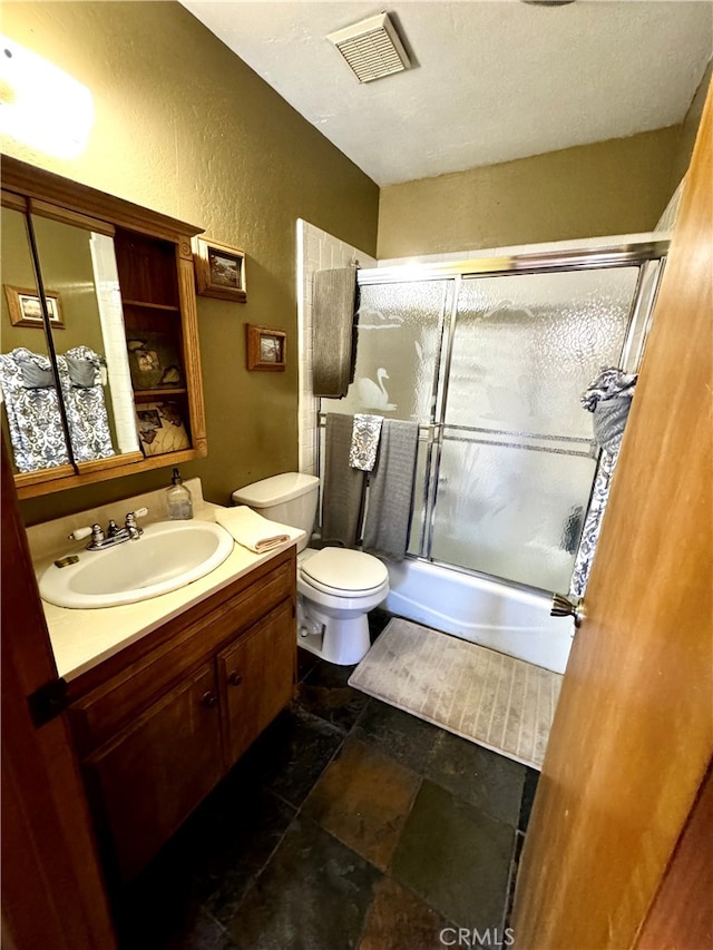 full bathroom featuring vanity, toilet, and shower / bath combination with glass door