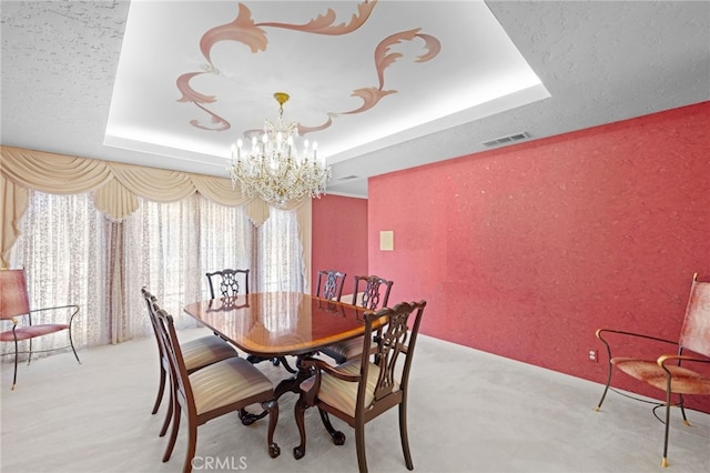 dining space featuring a tray ceiling, light carpet, and a chandelier