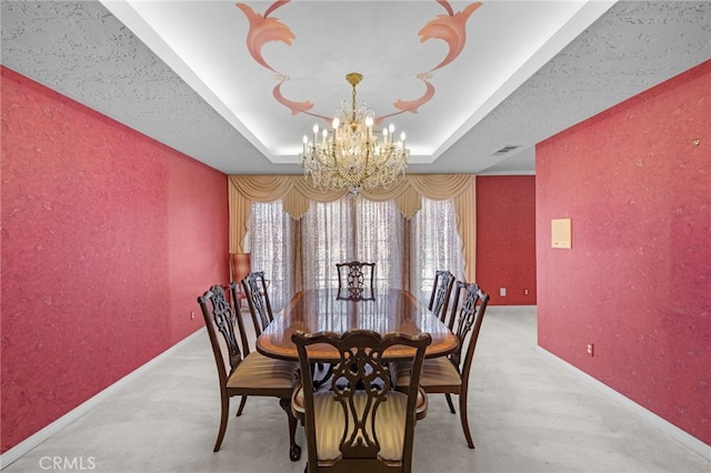 carpeted dining room featuring an inviting chandelier and a tray ceiling