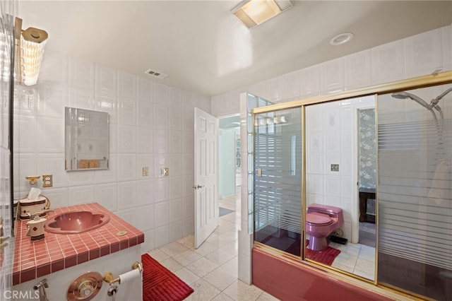 full bathroom with toilet, vanity, tile walls, tile patterned floors, and enclosed tub / shower combo