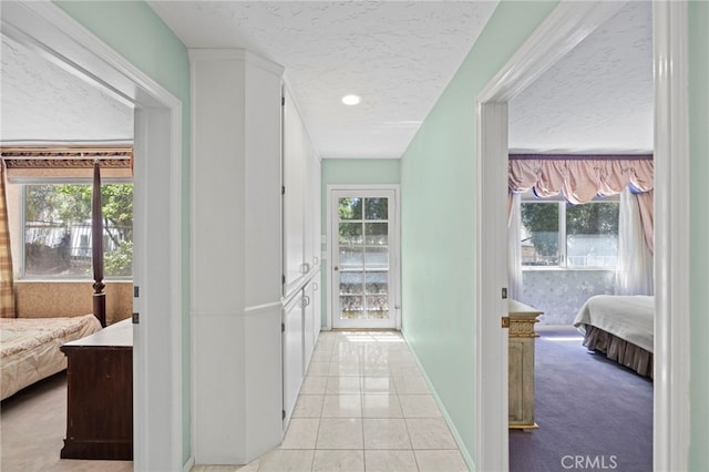 corridor featuring a textured ceiling and light tile patterned floors