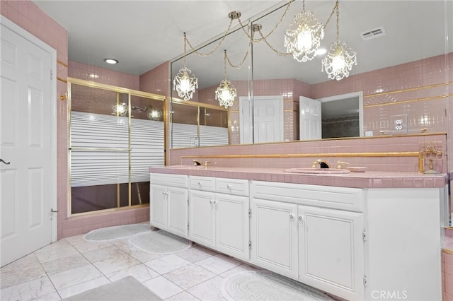 bathroom with tile patterned flooring, walk in shower, vanity, and tasteful backsplash