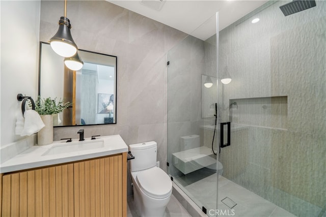 bathroom with vanity with extensive cabinet space, an enclosed shower, tile walls, tile floors, and toilet