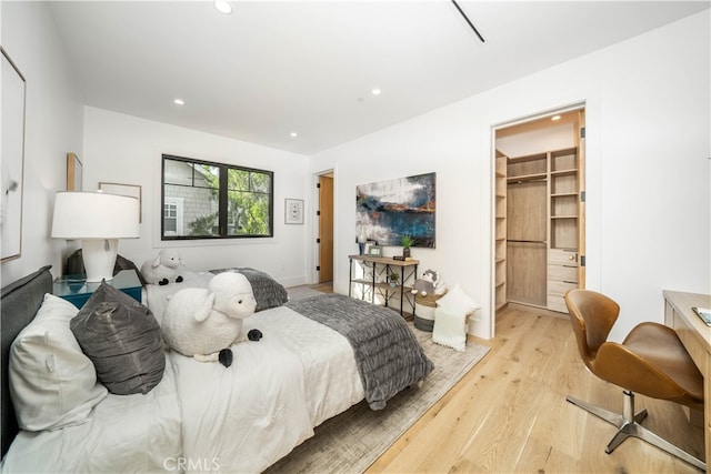 bedroom with a closet, light hardwood / wood-style floors, and a walk in closet