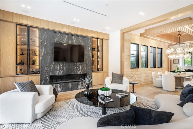 living room with a high end fireplace, an inviting chandelier, and wood-type flooring