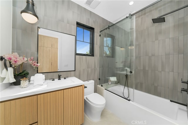 full bathroom with combined bath / shower with glass door, tile walls, toilet, tile flooring, and vanity