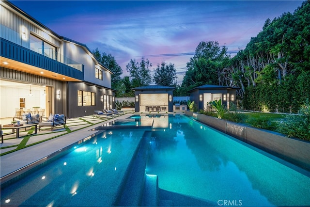 pool at dusk featuring an outdoor living space, a patio, and an outdoor structure