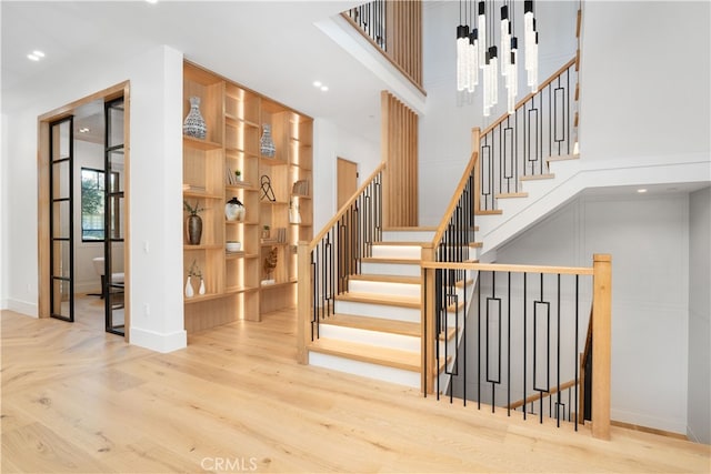 stairway with a chandelier and light hardwood / wood-style floors