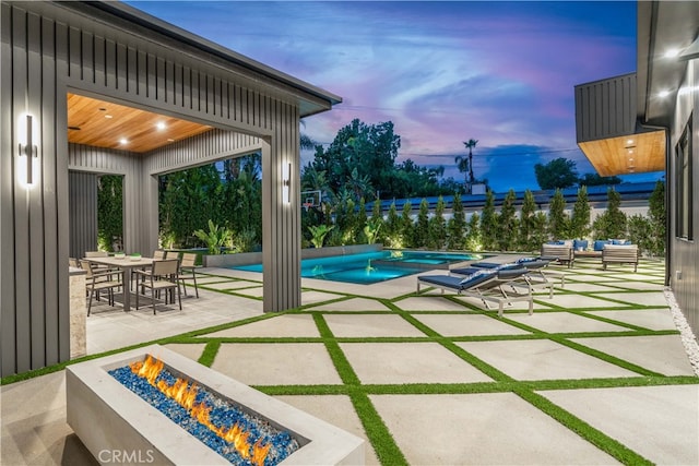 pool at dusk featuring a patio and a fire pit